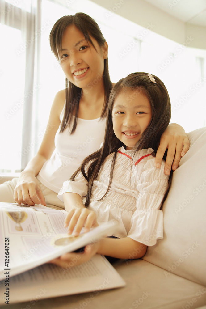 Mother and daughter, sitting side by side, looking at camera Mother and daughter, sitting side by side, looking at camera