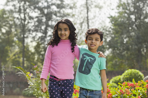 Canvas Print India, Young boy (4-5) and girl (6-7) standing with hands on shoulders in garden