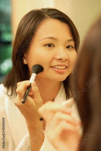 Woman putting on make-up with a blush brush