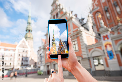 Photographing with smart phone famous houses of Blackheads and Peter church in the old town's center in Riga