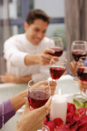 Friends toasting with wine glasses across dinner table