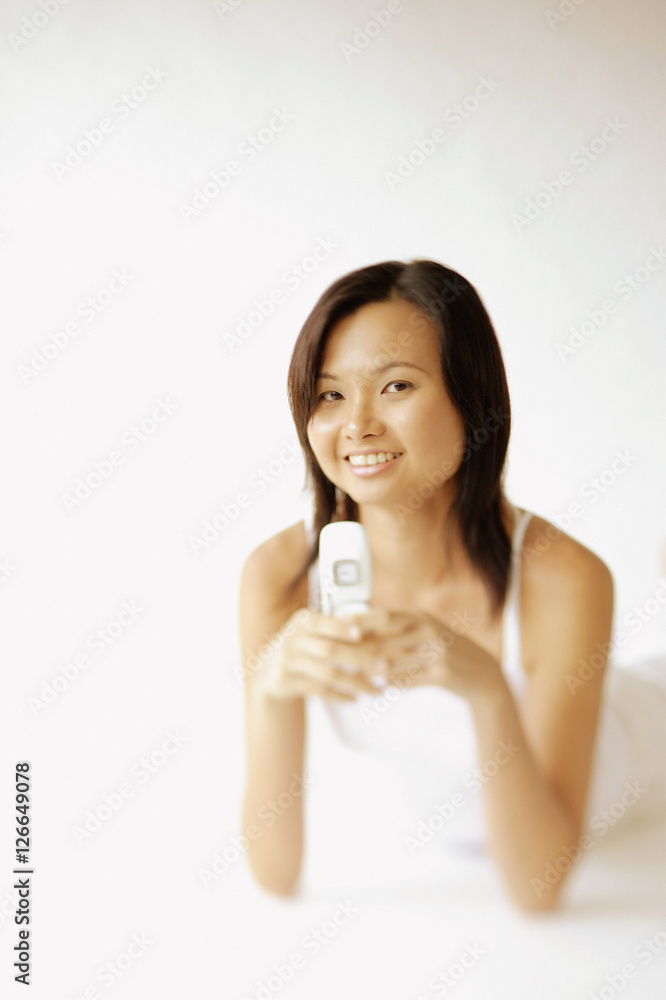 Young woman lying on floor, holding mobile phone Young woman lying on floor, holding mobile phone