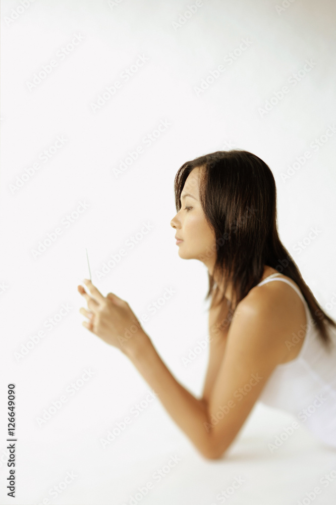 Young woman lying on floor, using mobile phone, sideview Young woman lying on floor, using mobile phone, sideview