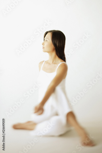 Young woman sitting on floor, looking away
