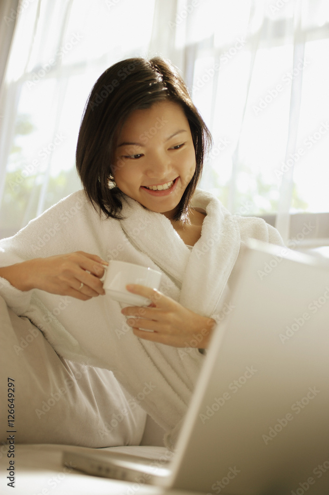 Young woman drinking coffee, laptop open in front of her Young woman drinking coffee, laptop open in front of her