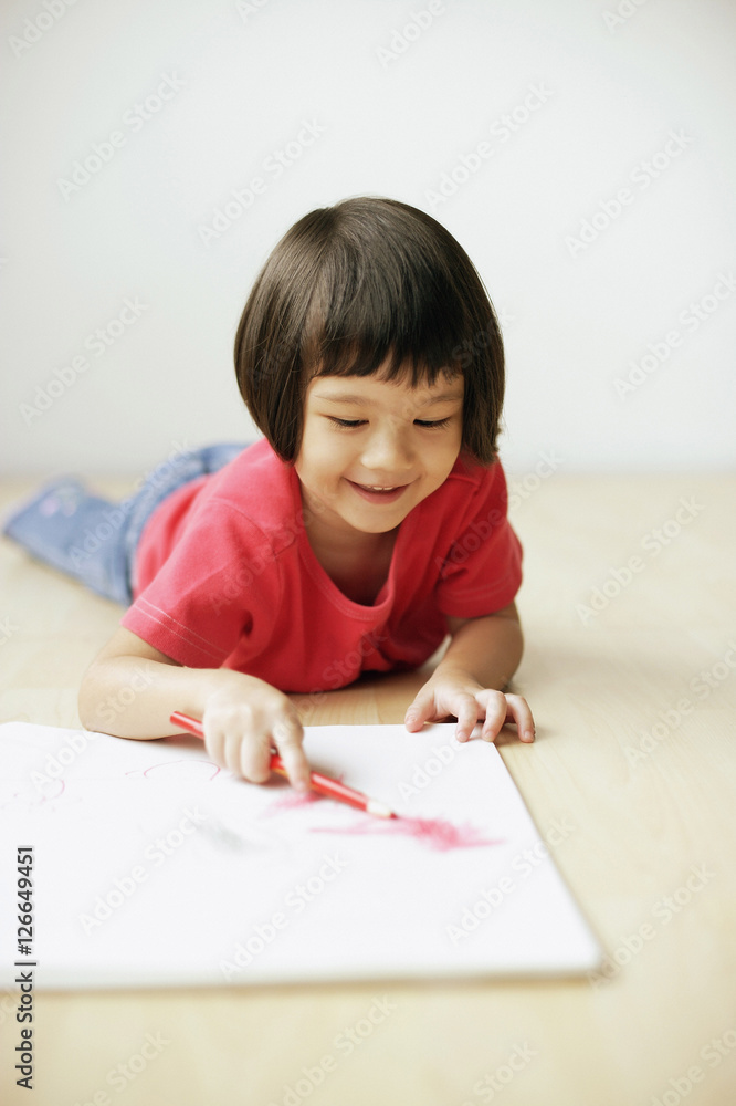 Young girl drawing on drawing pad, lying on front Young girl drawing on drawing pad, lying on front
