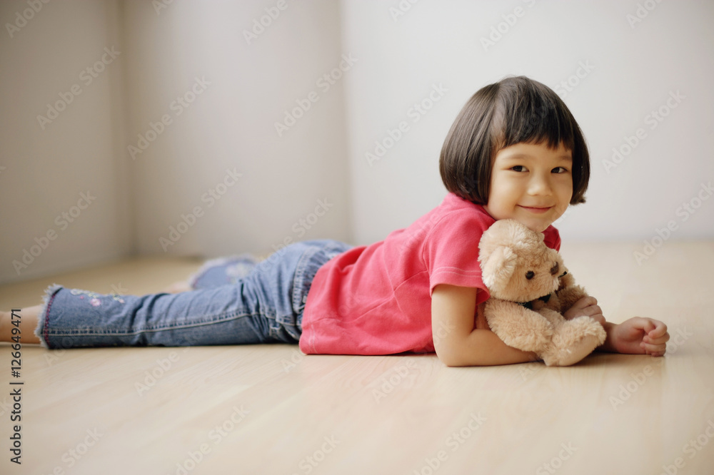 Young girl lying on front, hugging teddy bear. Young girl lying on front, hugging teddy bear.