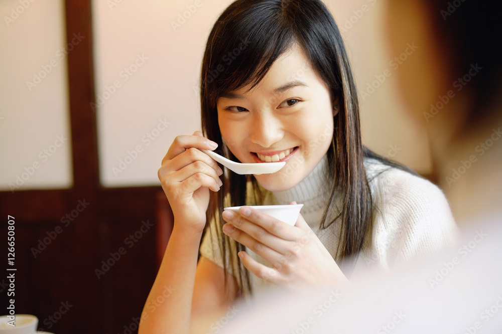 Young woman holding bowl, eating soup