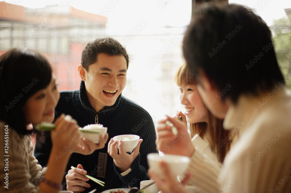 Group of friends eating at a Chinese restaurant, face to face
