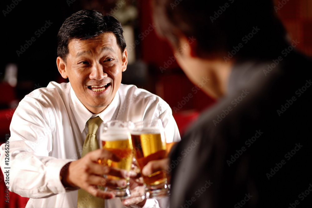 Two men toasting with beer glasses. Two men toasting with beer glasses.