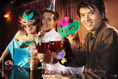 Couples with masks, holding drinks, looking at camera