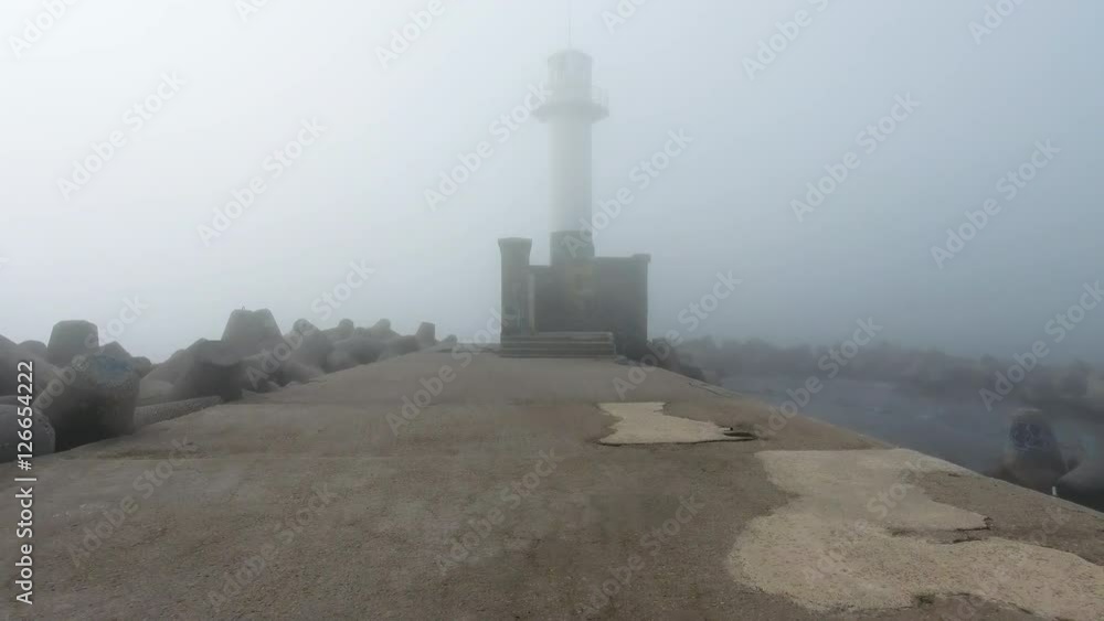Sunrise over Lighthouse in dense fog and mist, aerial view Sunrise over Lighthouse in dense fog and mist, aerial view