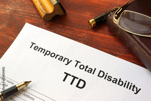 Temporary Total Disability (TTD) form on a wooden table. photo