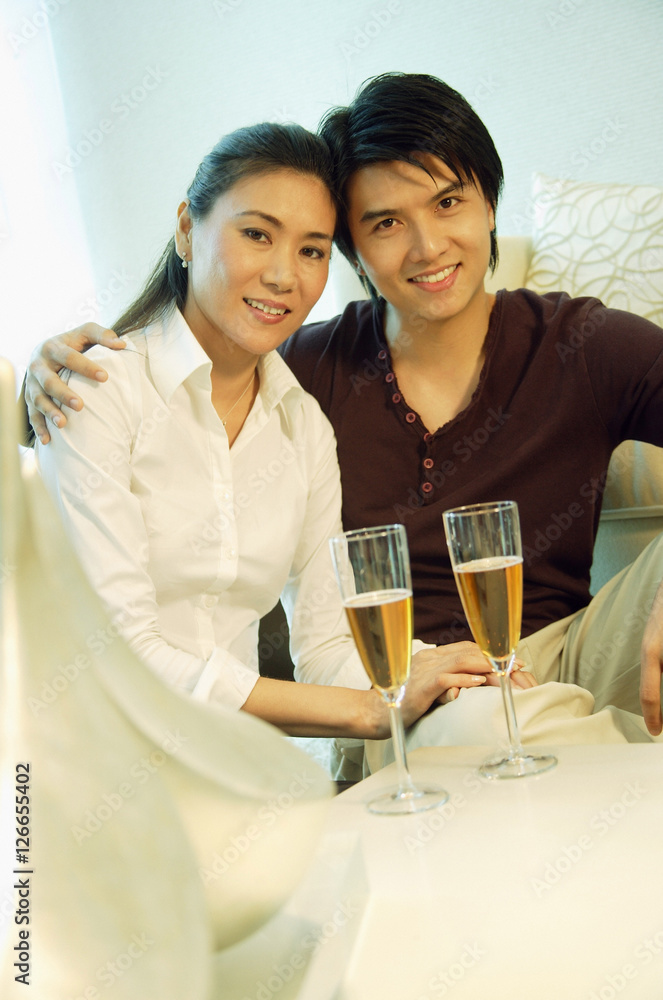 Couple looking at camera, champagne glasses in front of them Couple looking at camera, champagne glasses in front of them