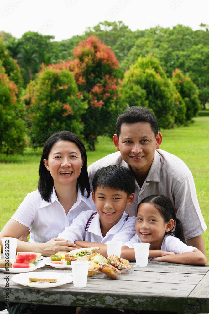 Family seated at picnic table, portrait Family seated at picnic table, portrait