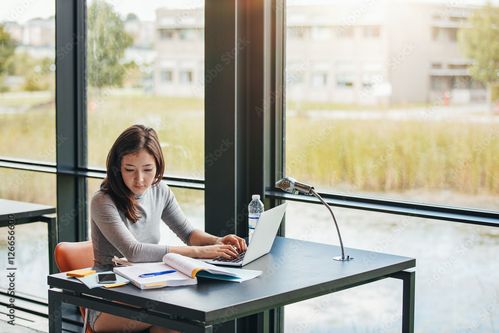 © Jacob Lund - Young asian woman in library doing assignments