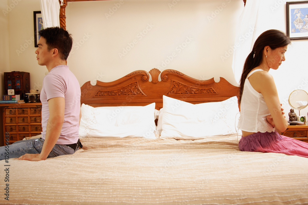 Couple apart at the edge of bed