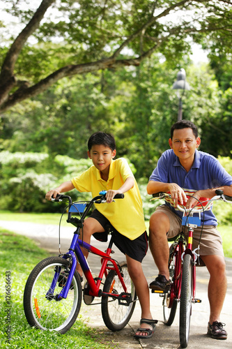 Father and son on bicycle, looking at camera
