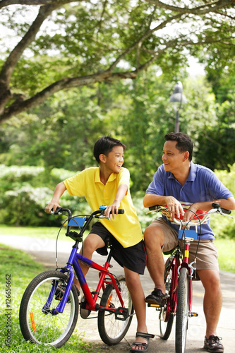 Father and son on bicycle, looking at each other