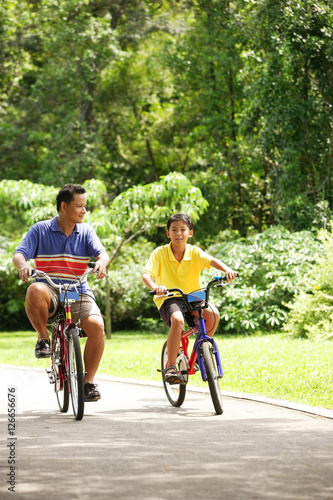 Father and son cycling, side by side