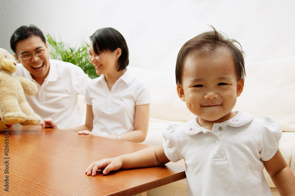 Father and mother in the background, daughter smiling, looking at camera