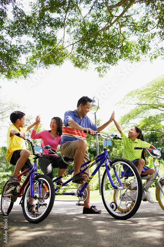 Family, on bicycles, giving each other high fives