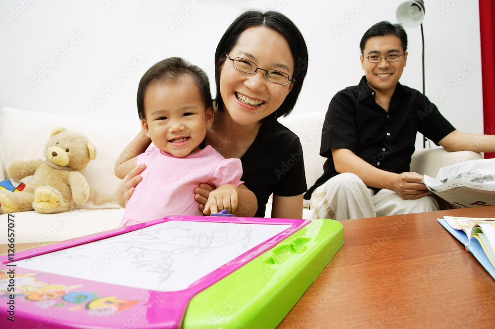 Family with one child in living room, looking at camera, portrait Family with one child in living room, looking at camera, portrait
