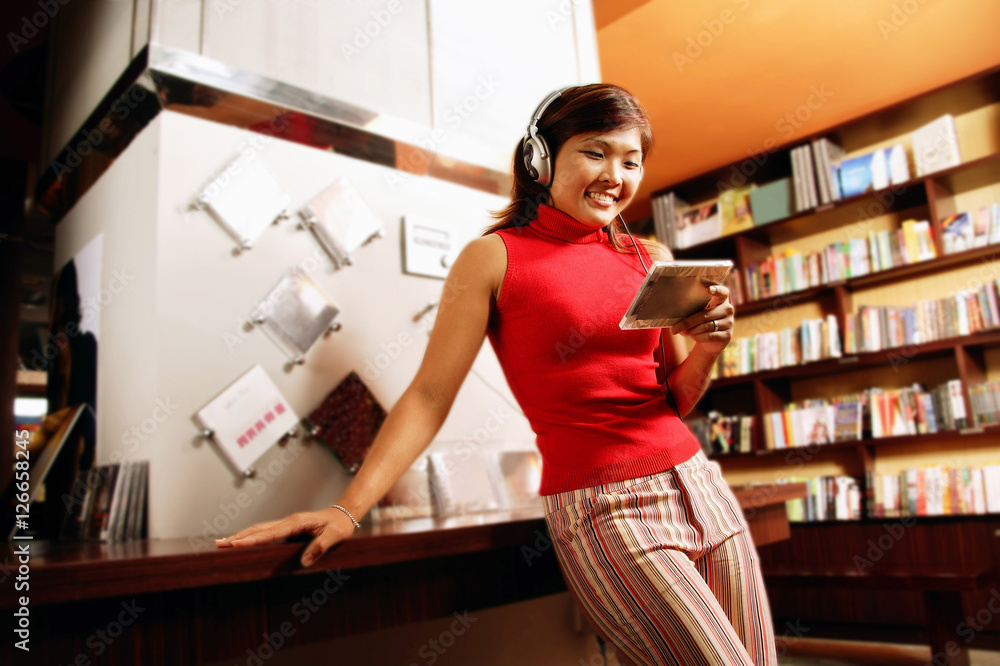 Young woman listening to music, smiling, leaning against counter