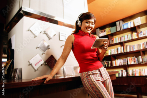 Obraz na płótnie Young woman listening to music, smiling, leaning against counter w salonie