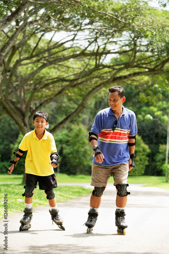 Fototapeta premium Father and son in park, on roller blades
