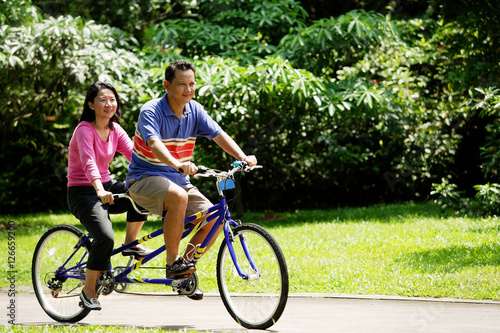 Couple riding tandem bicycle in park