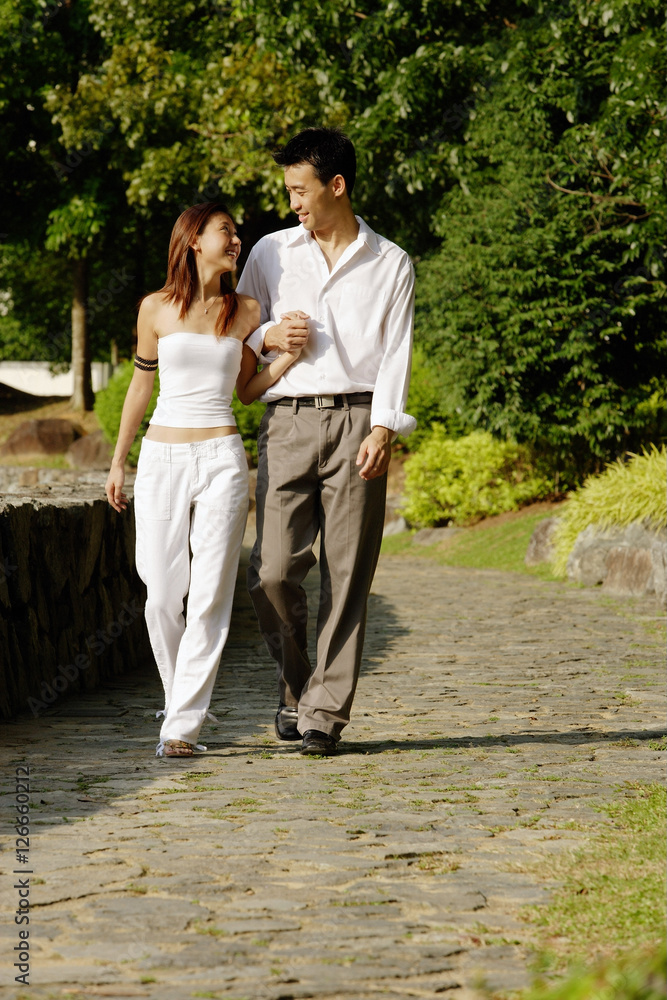 Couple walking through park, side by side, holding hands