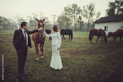 Cute wedding couple is posing with horses