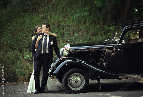 Beautiful wedding couple is posing near retro car © andriychuk