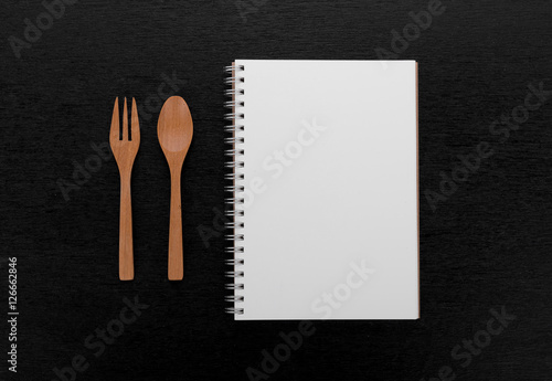 notebook and wooden spoon fork on black wooden background