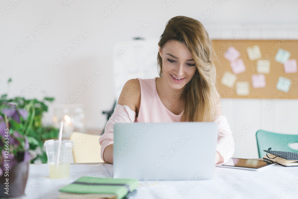 Young smiling businesswoman working in her office and typing on her laptop. Young smiling businesswoman working in her office and typing on her laptop.