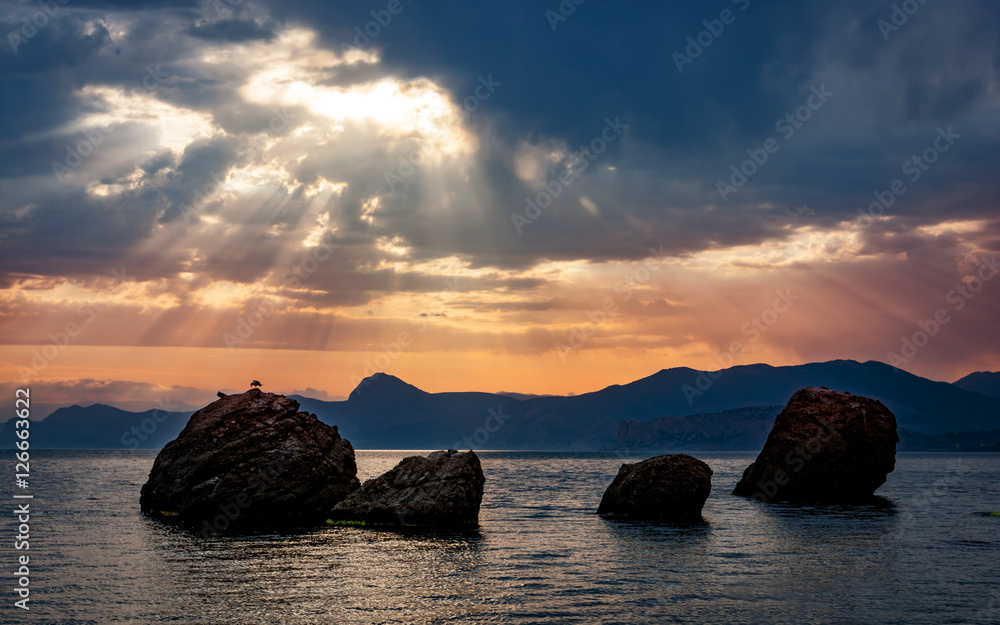 sunset over rocks in sea