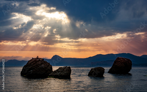 sunset over rocks in sea
