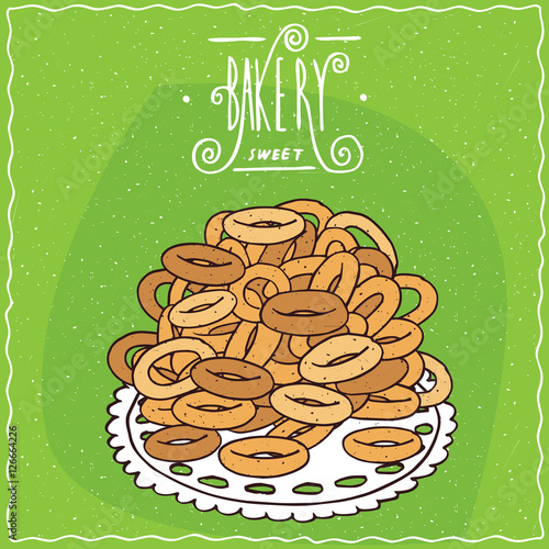 Classic Russian sweet bread rings sushki in heap, lie on lacy napkin. Green background and ornate lettering bakery. Handmade cartoon style