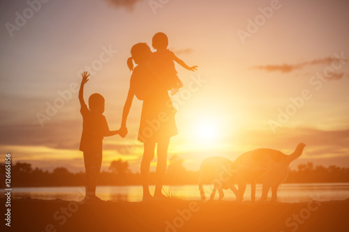 Mother encouraged her son outdoors at sunset, silhouette concept