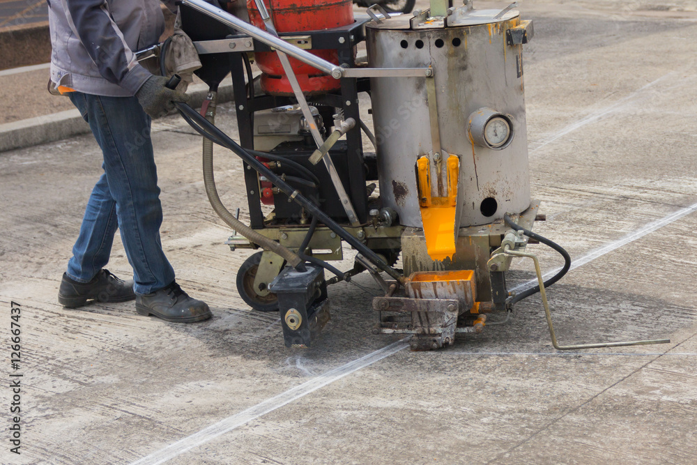 Man painting the yellow line on the concrete floor at car park Man painting the yellow line on the concrete floor at car park