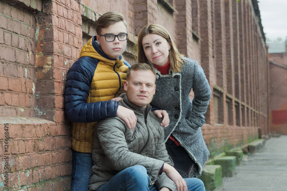 Family of three street portrait at red brick building wall background Family of three street portrait at red brick building wall background