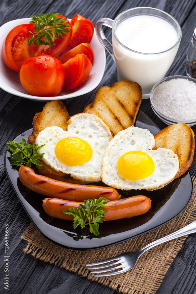 Breakfast on Valentine's Day - fried eggs in the shape of a heart and sausages. Top view