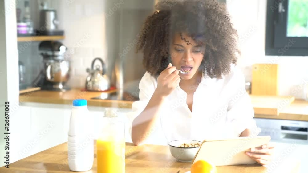 Mixed race woman sitting in kitchen having breakfast Mixed race woman sitting in kitchen having breakfast