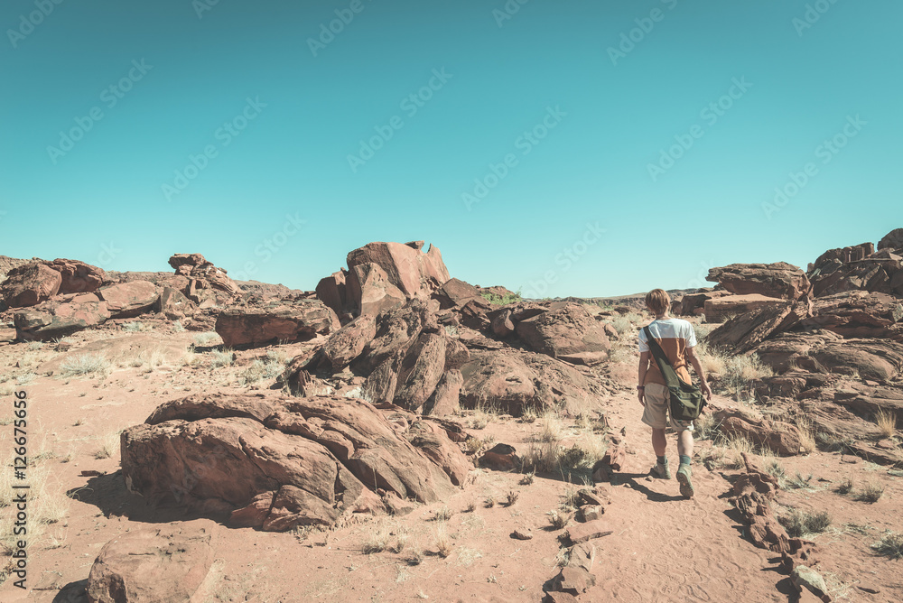 Tourist walking in the Namib desert, Namib Naukluft National Park, Namibia. Adventure and exploration in Africa. Toned image, vintage style cross processing. Tourist walking in the Namib desert, Namib Naukluft National Park, Namibia. Adventure and exploration in Africa. Toned image, vintage style cross processing.