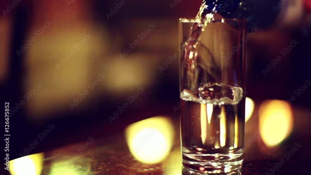 Drinking water is poured from a bottle into a glass in night bar. 1920x1080 Drinking water is poured from a bottle into a glass in night bar. 1920x1080