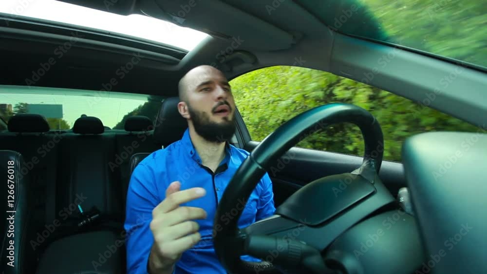 Young man with beard sings and dances during driving Young man with beard sings and dances during driving