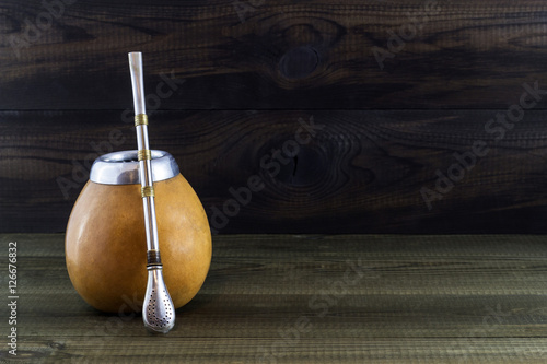 Yerba mate in gourd matero with bombila on wooden background. © marcinm111