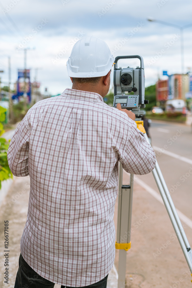 Obraz premium A surveyor at work with an infrared reflector used for distance measurement on roadside A land surveying professional is called a land surveyor.