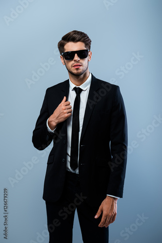 Stylish handsome man wearing black tuxedo and glasses